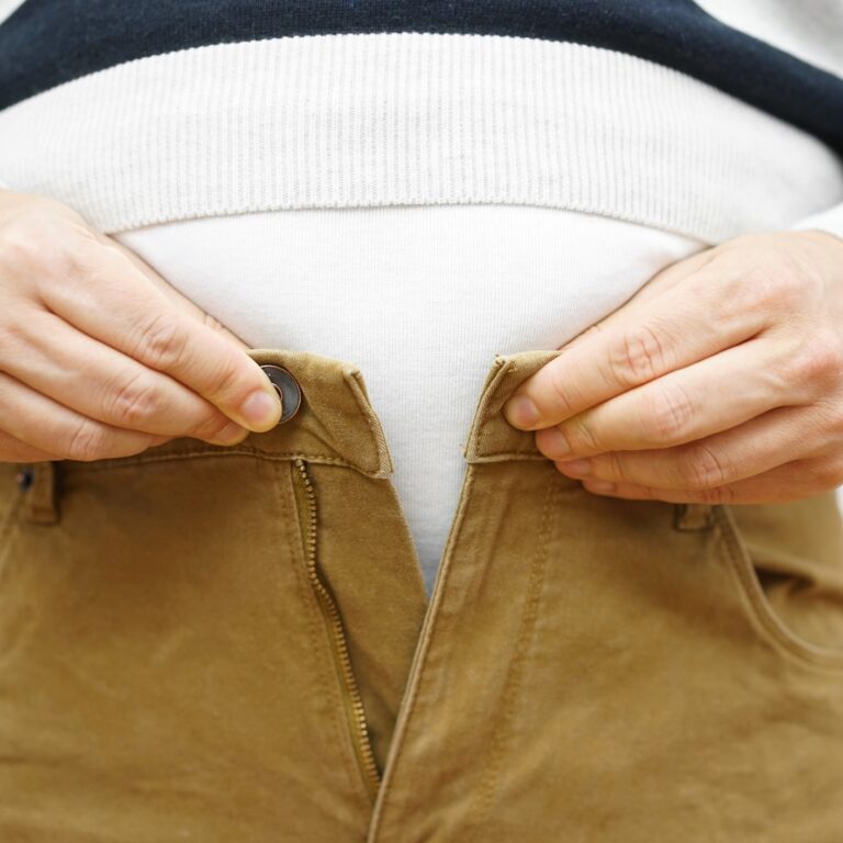 man is unable to close his pants because of gaining weight