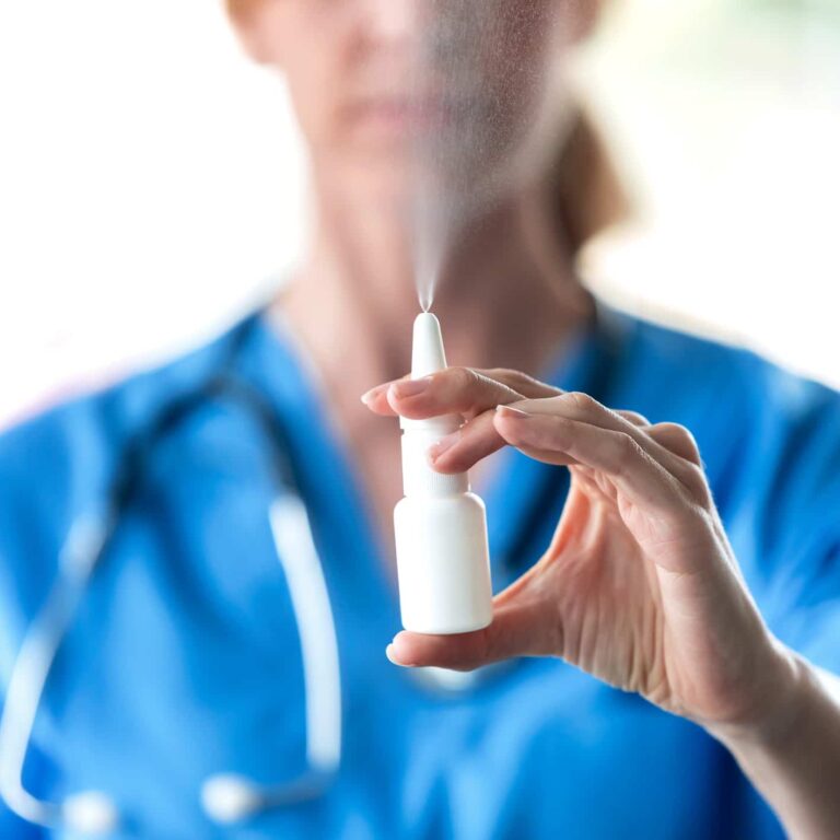 Close-up of female doctor with a spray or nasal drops for the treatment of a runny nose over white background.