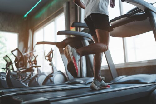 Why Most Americans are Losing the Battle of Getting into Pre-COVID Shape Close up of feet, sportman runner running on treadmill in fitness club. Cardio workout. Healthy lifestyle, guy training in gym. Sport running concept