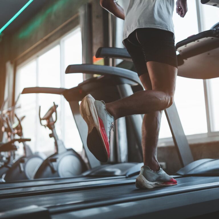 Close up of feet, sportman runner running on treadmill in fitness club. Cardio workout. Healthy lifestyle, guy training in gym. Sport running concept