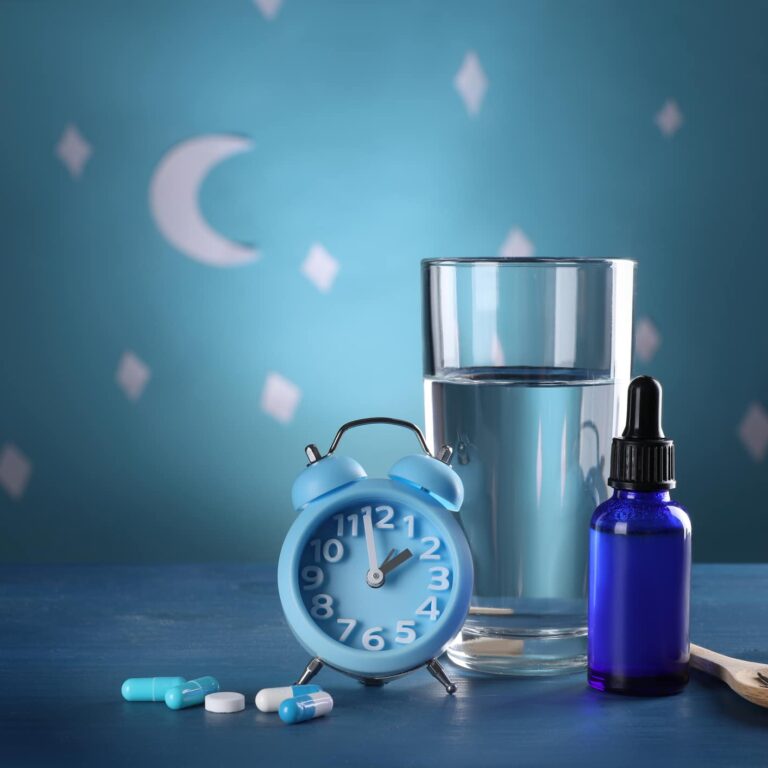 Alarm clock and different remedies for insomnia treatment near glass of water on table against blue wall decorated with stars and crescent