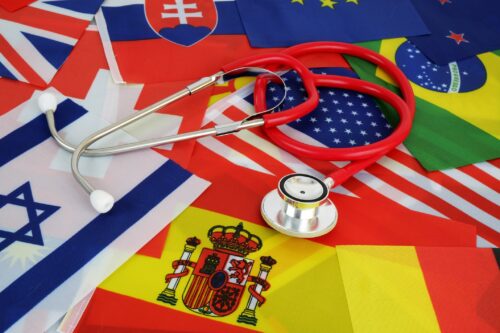 Medical tourism and medicine in different countries concept. Red stethoscope on national flags background.