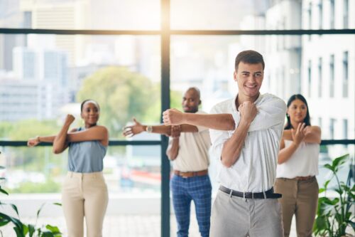 Workout, stretching and a group of business people in the office to exercise for health or mobility together. Fitness, wellness and coach training an employee team in the workplace for a warm up